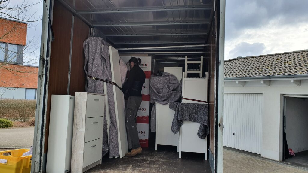 Mitarbeiter von Möbeltaxi Lüneburg sichert Ladung in einem LKW