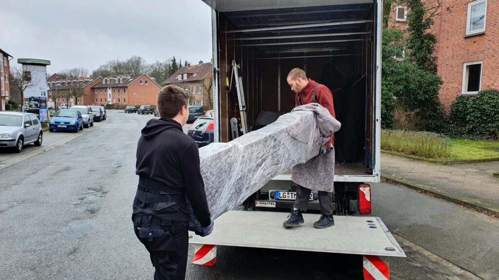 Mitarbeiter von Möbeltaxi Lüneburg tragen ein Möbelstück in einen LKW